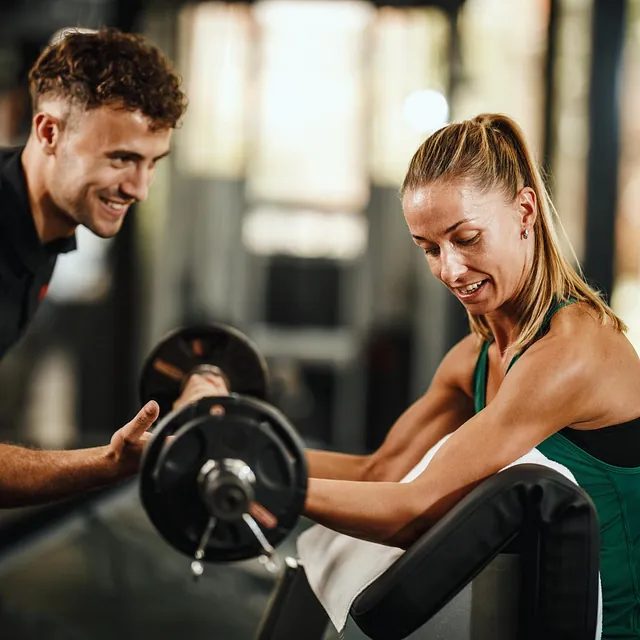 Personlig trener hjelper kvinne med bicepcurl